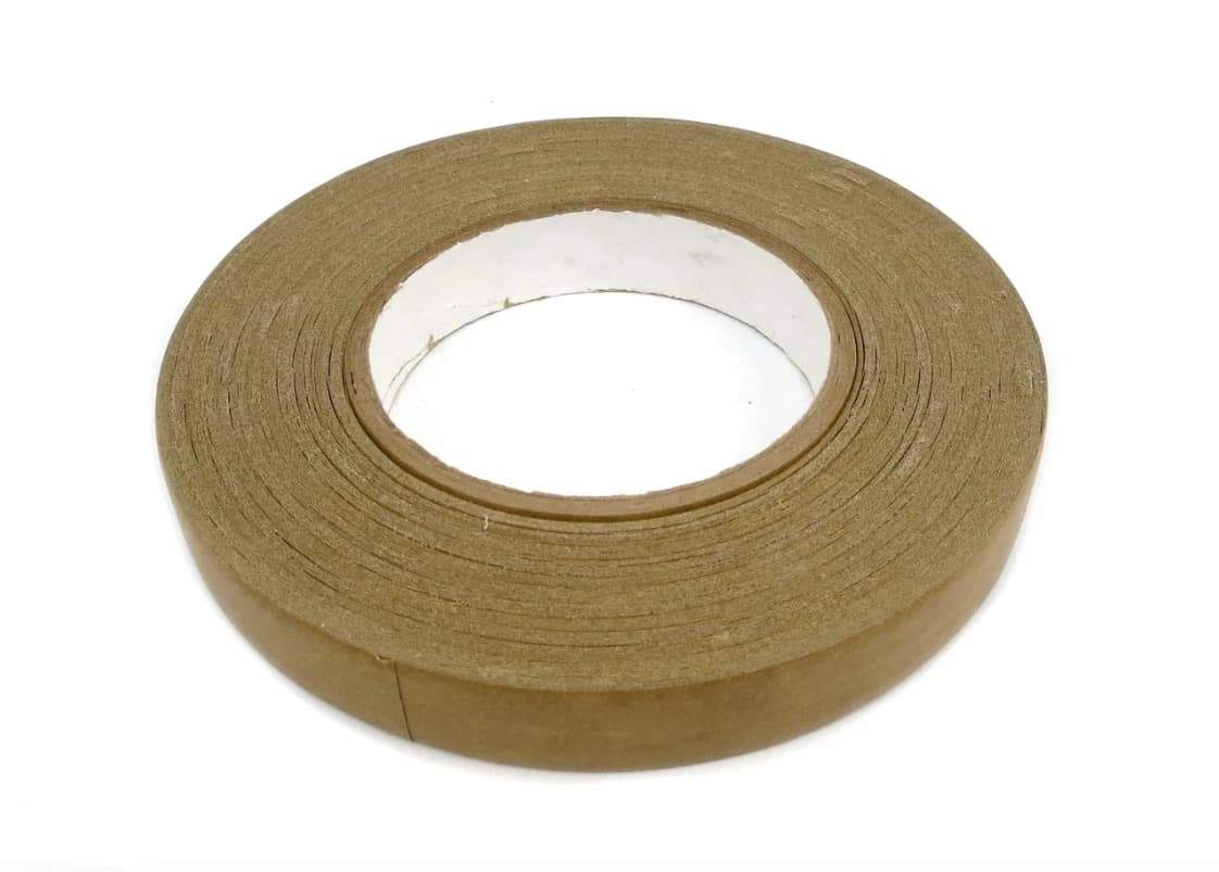 A roll of brown Kraft paper target pasting tape lying flat, seen from above at an angle, with the white cardboard core showing through the middle.