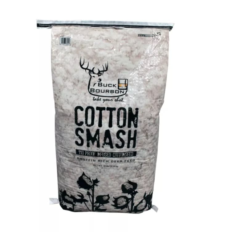 A 40 lb clear-plastic bag of Buck Bourbon Cotton Smash, whole cottonseed showing through, with the Buck Bourbon antlers-and-glass logo and cotton bolls printed in black.