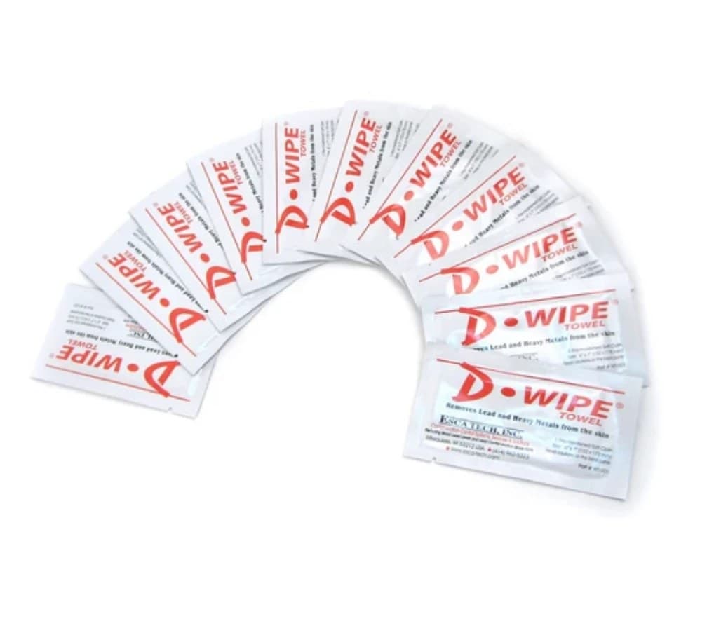 Ten individually sealed D-Wipe towel sachets fanned out in an arc on white, each white packet printed with the red D-Wipe Towel logo and the line about removing lead and heavy metals from the skin.