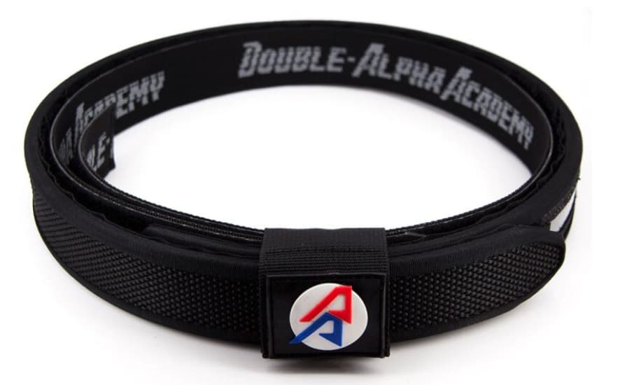 Double-Alpha Academy Premium Belt in black, coiled, with the red-and-blue DAA logo patch on the outer belt and the inner belt's lettering showing behind it.
