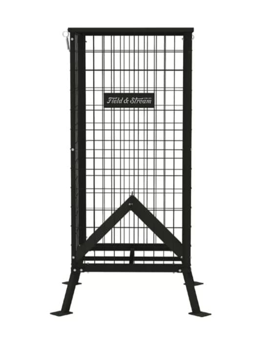 A Field & Stream 350 lb steel cottonseed deer feeder, a tall black welded-mesh cage on four splayed legs with a V-channel visible at the bottom and the Field & Stream badge on the front.