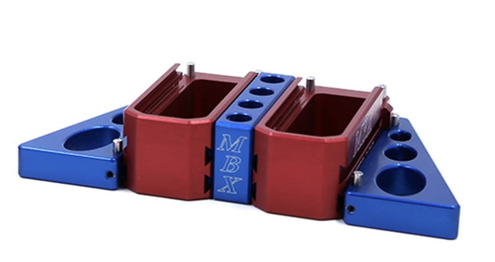 Two red MBX AR-15 extension basepads joined side by side by a blue MBX Inter-Loc block, with blue triangular stabilizer wings pinned to the outer ends, on white.