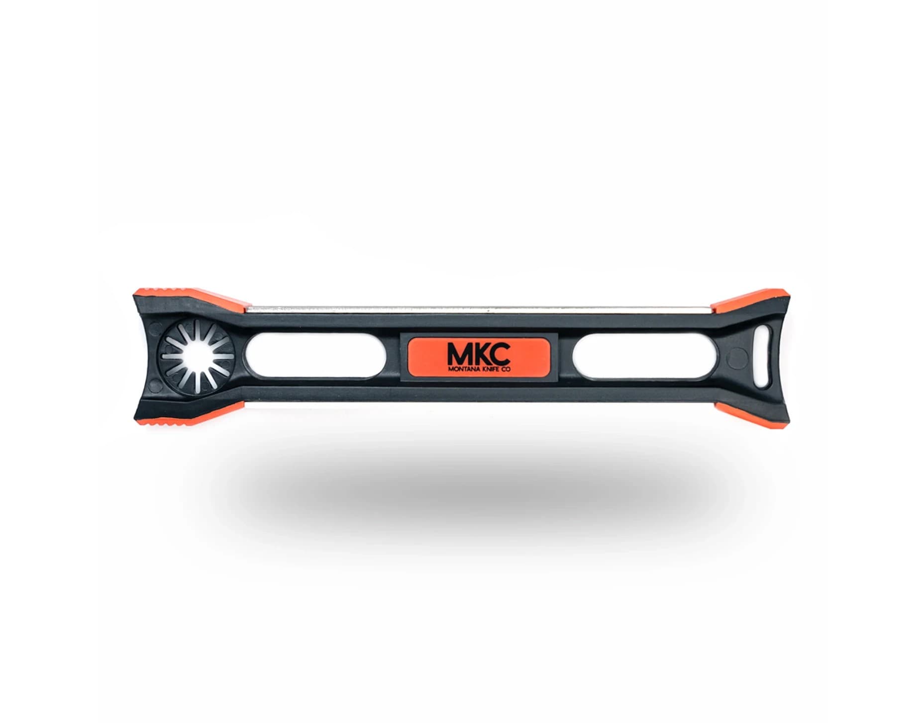 The MKC Field Knife Sharpener, a black bar with orange ends and an orange MKC Montana Knife Co badge, a sharpening rod along its top edge, a starburst cutout at one end and a lanyard slot at the other.