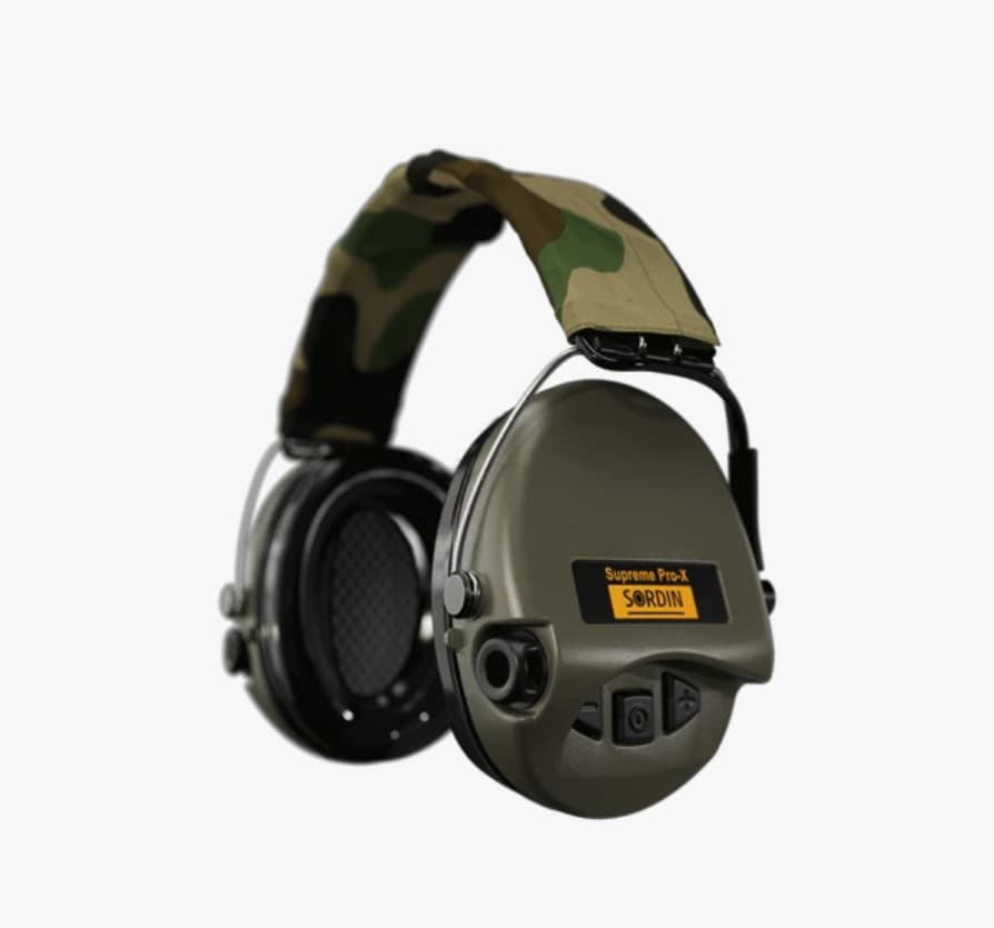Sordin Supreme Pro-X electronic earmuffs with green cups and a woodland-camo textile headband, seen from the front-right with the buttons and AUX port on the near cup.